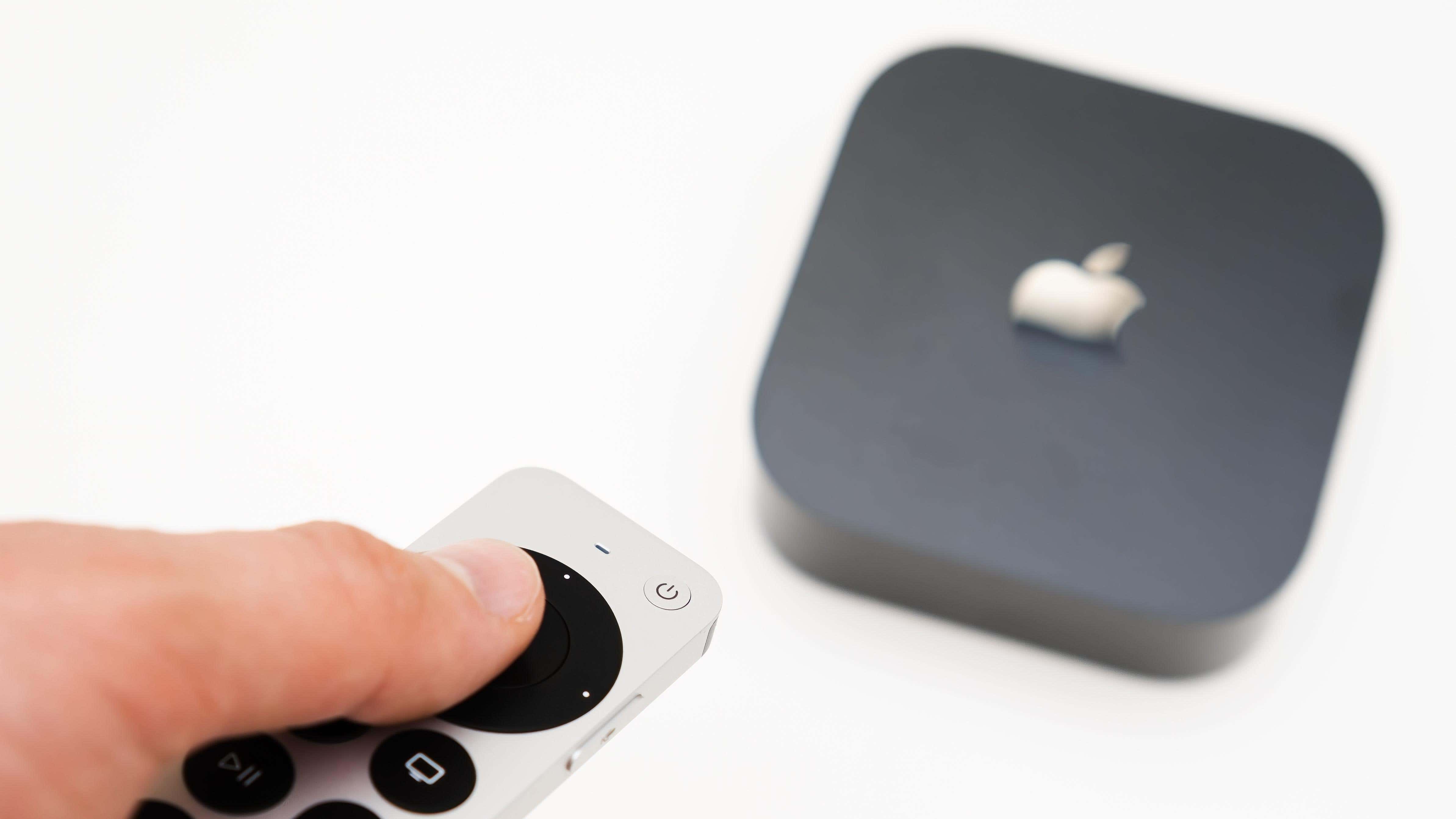 La mano del hombre enciende el nuevo streaming multimedia negro Apple TV 4K usando el control remoto
